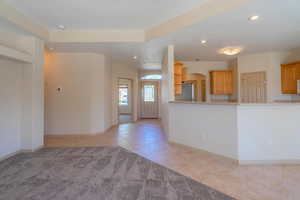 Unfurnished living room with light tile patterned floors, arched walkways, recessed lighting, and light carpet