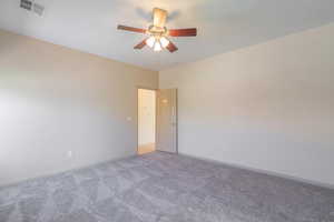 Carpeted spare room with baseboards and ceiling fan