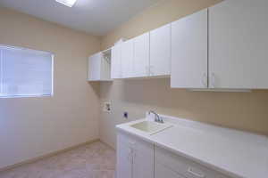 Washroom featuring cabinet space, hookup for a washing machine, electric dryer hookup, and light tile patterned flooring