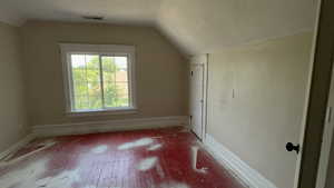 Additional living space with a textured ceiling, hardwood / wood-style floors, and vaulted ceiling