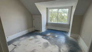 Additional living space with a textured ceiling, hardwood / wood-style floors, and vaulted ceiling