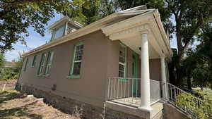 View of side of property with a porch, crawl space, and brick siding