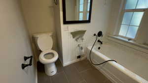 Bathroom with tub / shower combination and dark tile patterned flooring