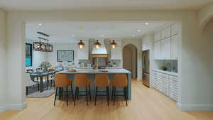 Kitchen featuring arched walkways, a kitchen breakfast bar, pendant lighting, white cabinetry, and recessed lighting