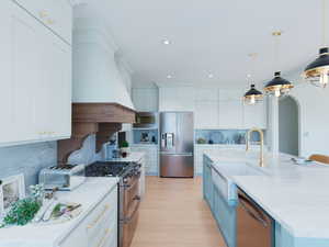 Kitchen with white cabinets, stainless steel appliances, light stone counters, arched walkways, and recessed lighting