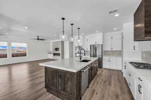 Kitchen with dark brown cabinetry, decorative backsplash, white cabinetry, light wood finished floors, and recessed lighting