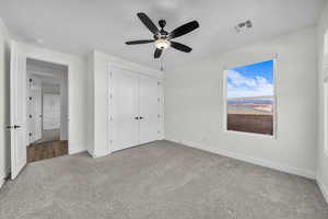 Unfurnished bedroom with light carpet, a closet, and a ceiling fan