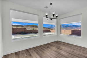 Unfurnished dining area featuring wood finished floors, a chandelier, and a mountain view