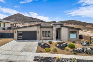 Contemporary home featuring stone siding, concrete driveway, stucco siding, and a mountain view