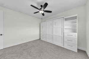 Unfurnished bedroom with light colored carpet and ceiling fan