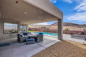 Fenced backyard with a patio area, a mountain view, an outdoor hangout area, and a pool with connected hot tub
