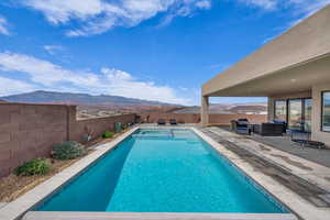 View of swimming pool featuring a fenced backyard, a mountain view, an outdoor living space, and a patio