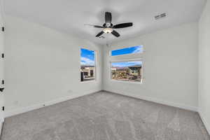 Carpeted empty room with baseboards and a ceiling fan