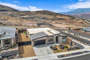 View of front of property with a mountain view, driveway, stucco siding, and a garage