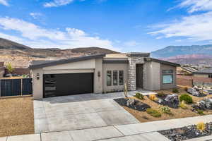 View of front of home with a mountain view, stucco siding, driveway, a garage, and stone siding