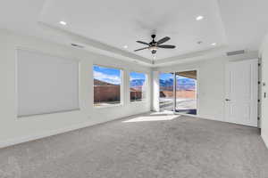 Spare room with a raised ceiling, light carpet, and recessed lighting