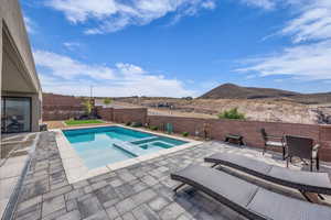 View of pool featuring a fenced backyard, a pool with connected hot tub, a patio area, and a mountain view