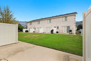 Back of property with a mountain view and a partially fenced patio