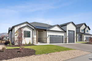 Modern inspired farmhouse featuring board and batten siding, an attached garage, concrete driveway, a front lawn, and roof with shingles