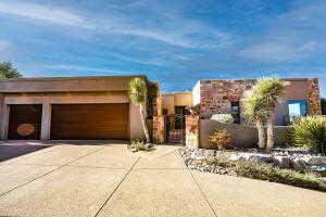 Pueblo revival-style home featuring a gate, driveway, a fenced front yard, and stucco siding