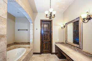 Full bath featuring a garden tub, vanity, a chandelier, and light tile patterned flooring