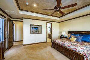 Bedroom with a tray ceiling, light carpet, crown molding, a ceiling fan, and connected bathroom