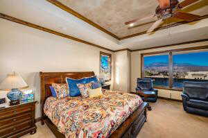 Bedroom with light colored carpet, ornamental molding, a raised ceiling, and ceiling fan