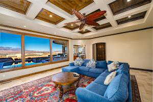 Living area featuring beamed ceiling, coffered ceiling, arched walkways, ornamental molding, and ceiling fan