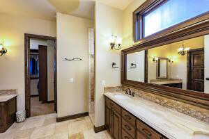 Full bath with vanity, a chandelier, and a walk in closet
