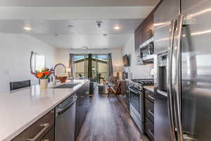Kitchen with appliances with stainless steel finishes, open floor plan, a textured ceiling, dark brown cabinetry, and recessed lighting