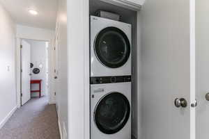 Washroom featuring carpet flooring and stacked washer / dryer