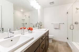 Bathroom with a shower stall, double vanity, and light tile patterned floors