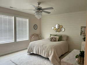 Bedroom with a ceiling fan, wood walls, and wood finished floors