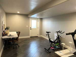 Exercise room featuring a textured ceiling, recessed lighting, and dark tile patterned flooring