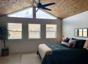Bedroom featuring multiple windows, wood finished floors, wooden ceiling, wood walls, and a ceiling fan