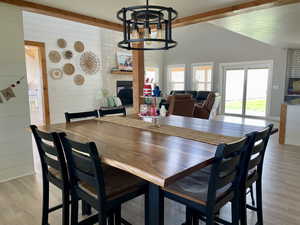 Dining room with light wood-style floors, a large fireplace, a chandelier, and wood walls