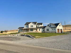 Modern farmhouse style home with covered porch, board and batten siding, a garage, and a front lawn