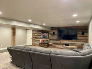 Living room with wood walls, recessed lighting, and a textured ceiling