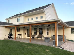 Rear view of house featuring ceiling fan, a patio, and a lawn