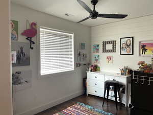 Office area with dark wood-type flooring, ceiling fan, and wooden walls