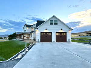 View of side of home featuring a porch, concrete driveway, a yard, and a garage