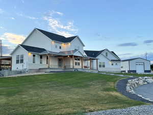 Modern inspired farmhouse featuring a lawn, a porch, an outdoor structure, board and batten siding, and a metal roof