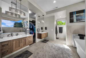 Bathroom with two vanities, a walk in closet, backsplash, light tile patterned flooring, and recessed lighting