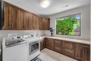 Laundry area with cabinet space, washing machine and clothes dryer, and light tile patterned flooring