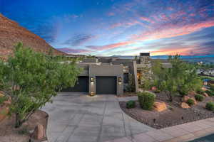 View of front facade with stucco siding, a mountain view, driveway, and a garage