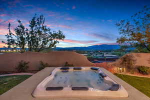 Patio terrace at dusk featuring a hot tub and a mountain view