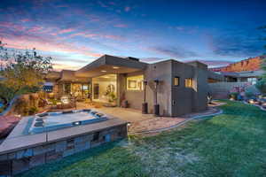 Back of property with a patio area, stucco siding, and an outdoor hot tub