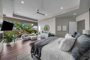 Bedroom with a tray ceiling, recessed lighting, access to outside, wood finished floors, and a ceiling fan