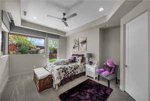 Bedroom with a raised ceiling, ceiling fan, recessed lighting, and access to outside