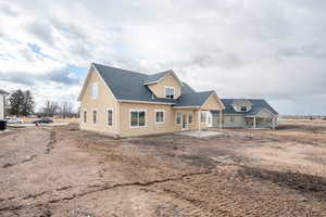 Back of property featuring a patio area, stucco siding, and roof with shingles